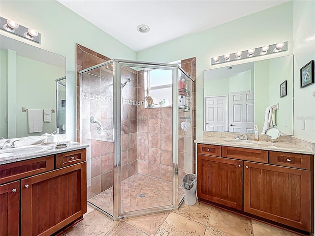 bathroom with a shower stall, two vanities, and a sink