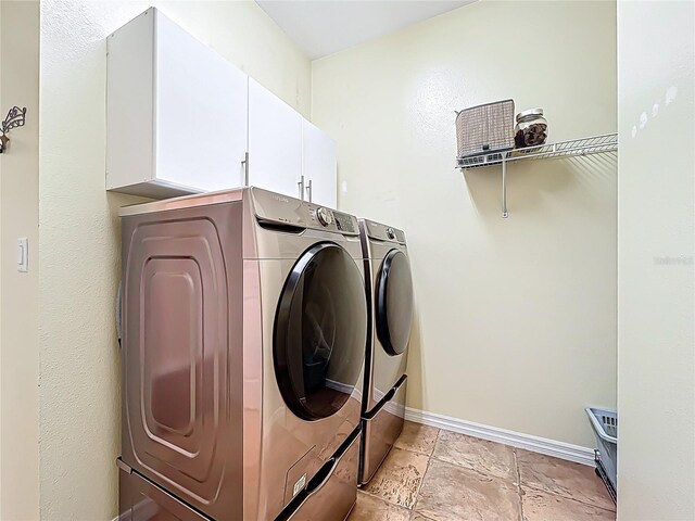 laundry area with baseboards, cabinet space, and independent washer and dryer