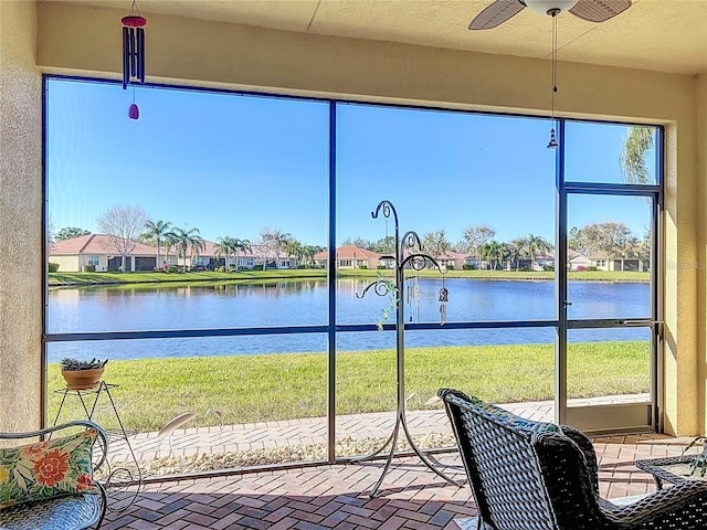 unfurnished sunroom featuring a water view and ceiling fan