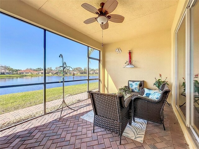 sunroom / solarium featuring a ceiling fan and a water view