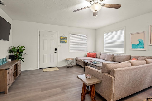 living room featuring visible vents, baseboards, light wood-type flooring, and a ceiling fan