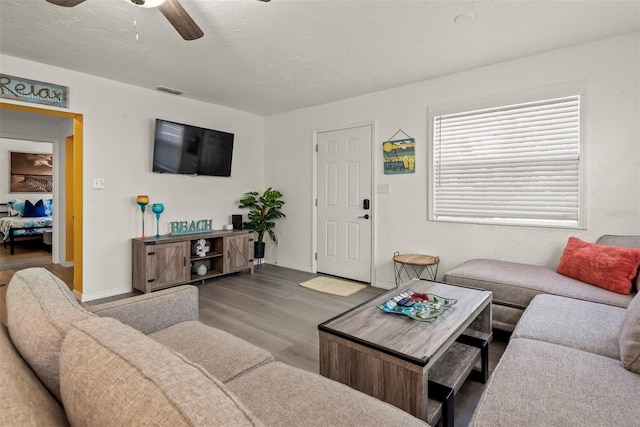 living area with baseboards, wood finished floors, a textured ceiling, and ceiling fan