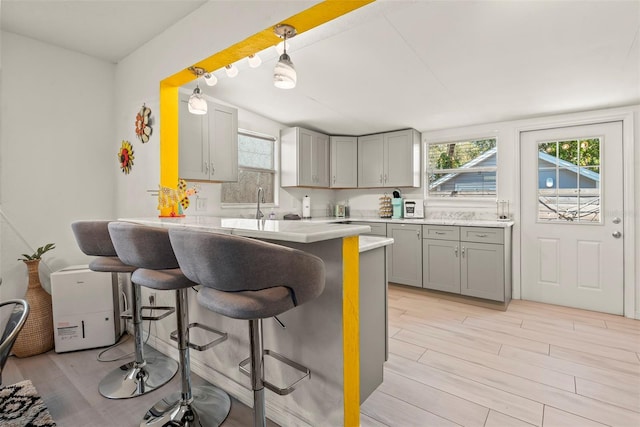 kitchen with gray cabinets, a peninsula, a breakfast bar, and a healthy amount of sunlight