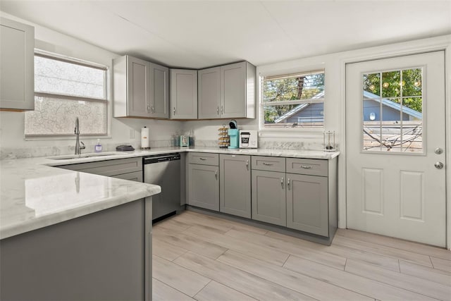 kitchen with light stone countertops, wood tiled floor, a sink, gray cabinetry, and dishwasher