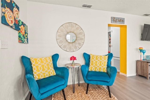 living area with visible vents, baseboards, and wood finished floors