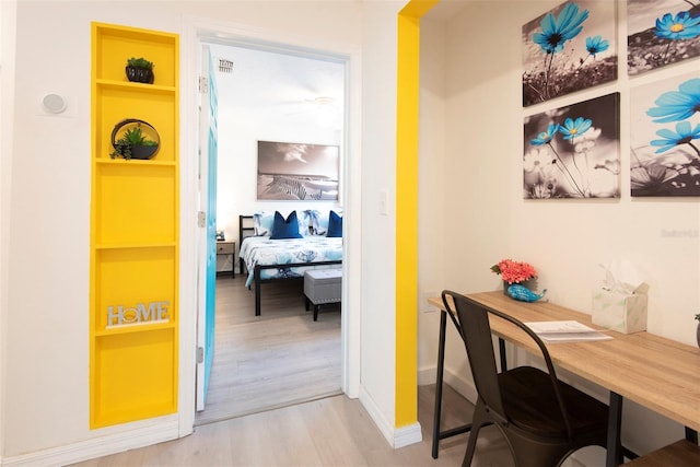 hallway with built in features, baseboards, visible vents, and light wood-type flooring