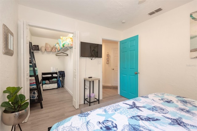 bedroom featuring a closet, visible vents, a walk in closet, and light wood-style floors