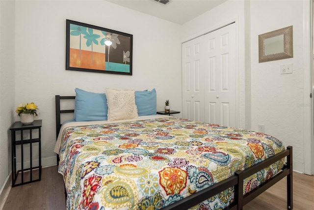 bedroom featuring a closet, baseboards, visible vents, and wood finished floors