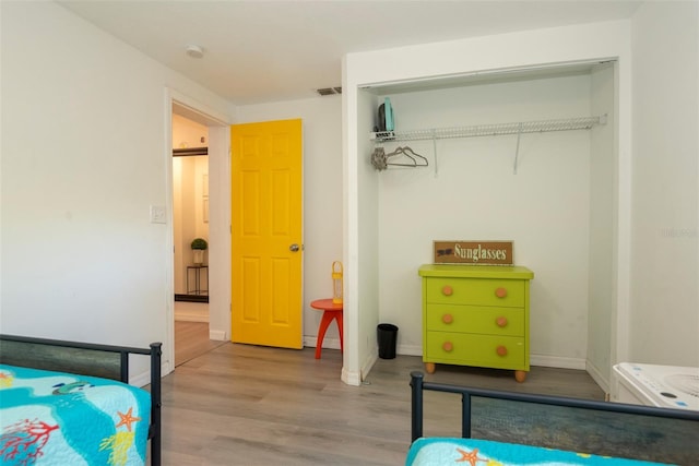 bedroom featuring a closet, visible vents, baseboards, and wood finished floors