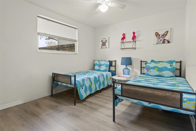 bedroom with ceiling fan, baseboards, and wood finished floors