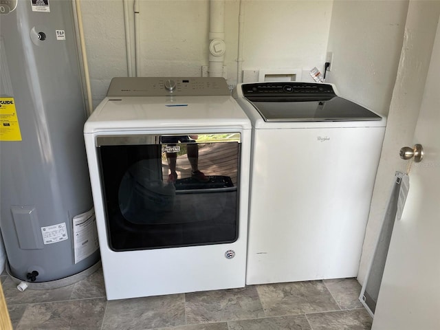 laundry room with washer and dryer, laundry area, water heater, and stone finish flooring