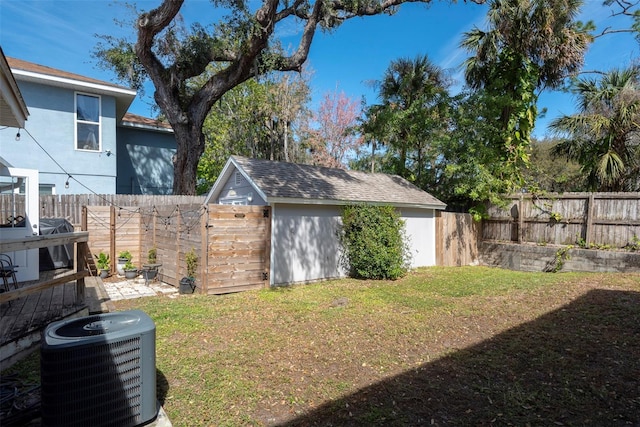 view of yard featuring a fenced backyard, an outbuilding, and central AC