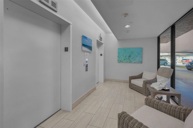 hallway with wood tiled floor, elevator, floor to ceiling windows, and baseboards