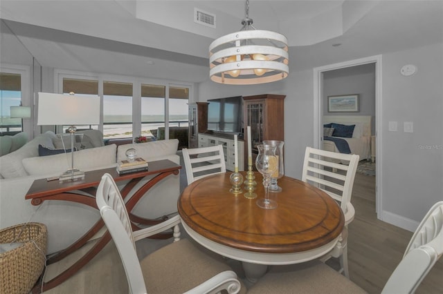 dining area featuring baseboards, wood finished floors, visible vents, and a notable chandelier