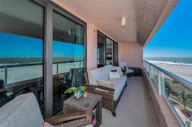 balcony with a view of the beach, a sunroom, and a water view