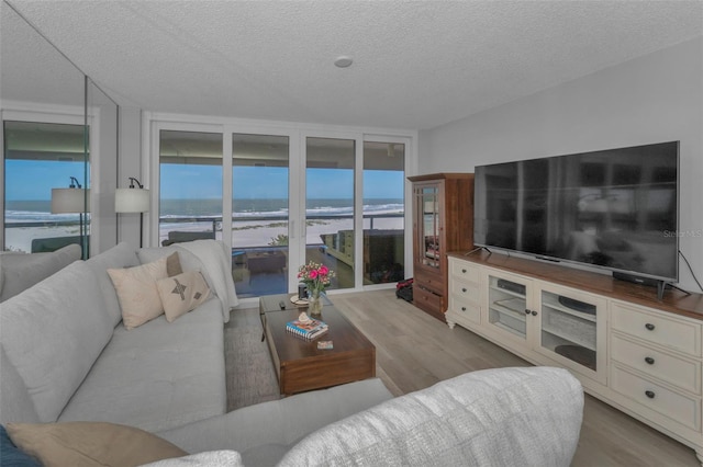 living area with floor to ceiling windows, a textured ceiling, and wood finished floors