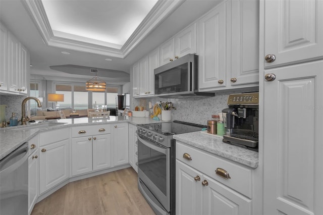 kitchen featuring appliances with stainless steel finishes, light wood-type flooring, a raised ceiling, and white cabinetry