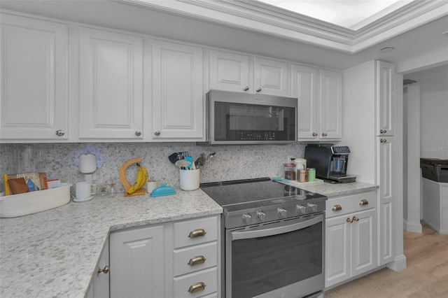 kitchen featuring light wood-style flooring, appliances with stainless steel finishes, ornamental molding, white cabinetry, and backsplash