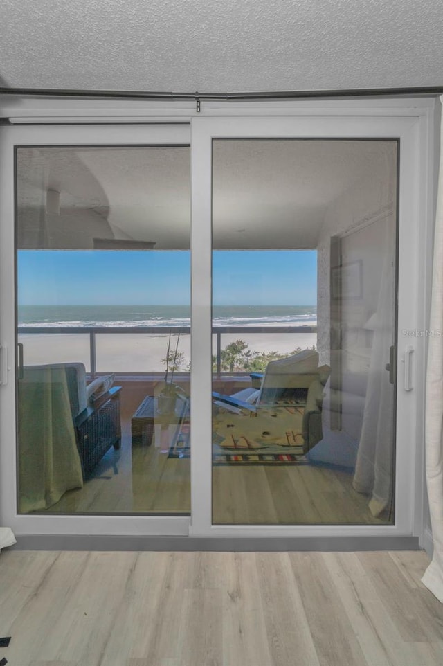 doorway featuring a water view, a textured ceiling, and wood finished floors