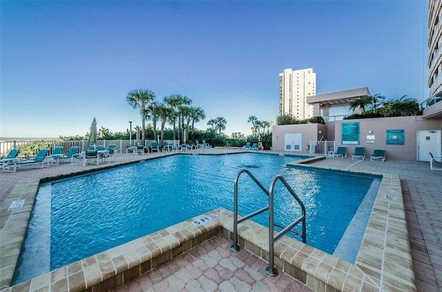 community pool with a patio area and fence