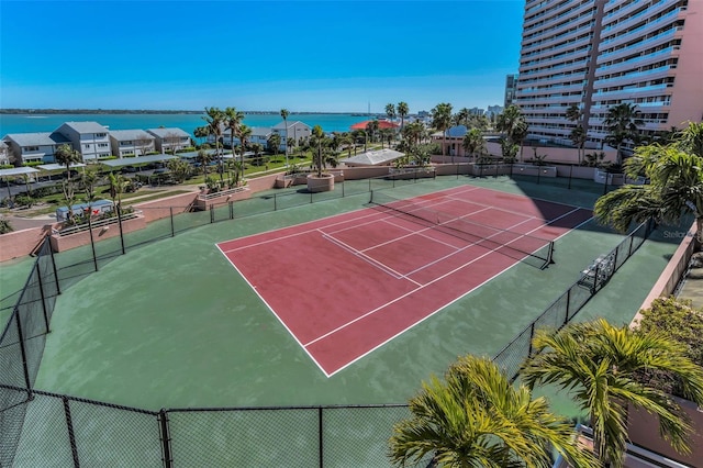 view of sport court with a water view and fence