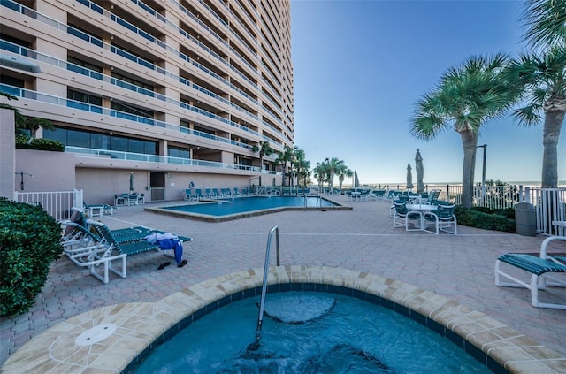 pool with a patio area, fence, and a community hot tub