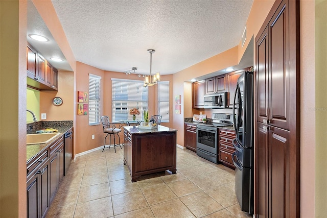 kitchen featuring pendant lighting, a sink, a kitchen island, appliances with stainless steel finishes, and light tile patterned floors