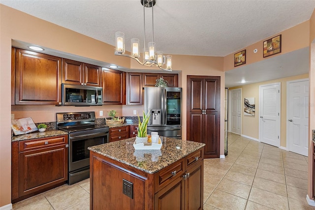 kitchen with dark stone counters, light tile patterned floors, appliances with stainless steel finishes, and a kitchen island