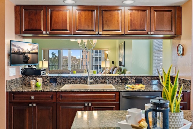 kitchen with dark stone countertops, dishwasher, and a sink