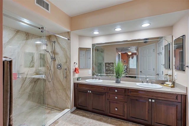 bathroom featuring a marble finish shower, visible vents, double vanity, and a sink