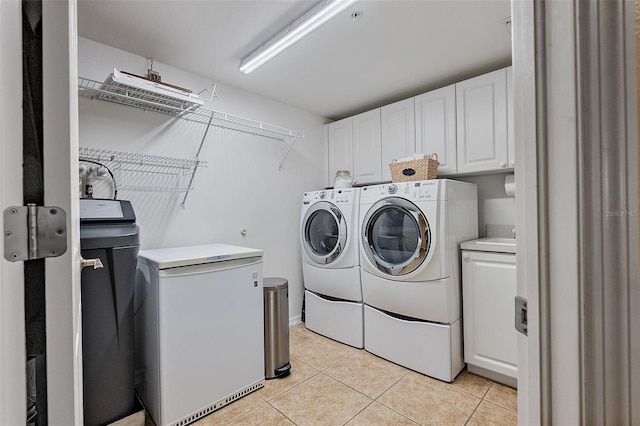 washroom featuring light tile patterned floors, cabinet space, and washing machine and clothes dryer