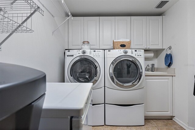 laundry room with visible vents, baseboards, washing machine and dryer, light tile patterned flooring, and cabinet space