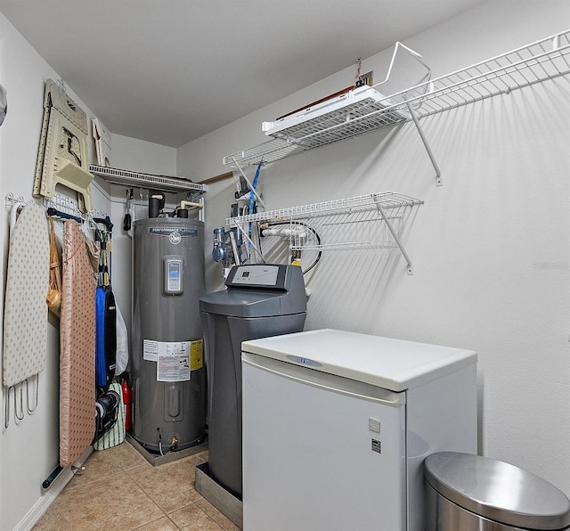 laundry area featuring light tile patterned floors, electric water heater, washing machine and dryer, and laundry area