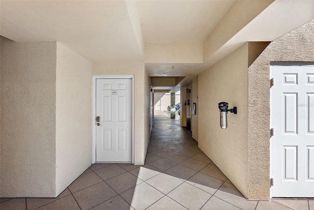 corridor with light tile patterned floors and a textured wall