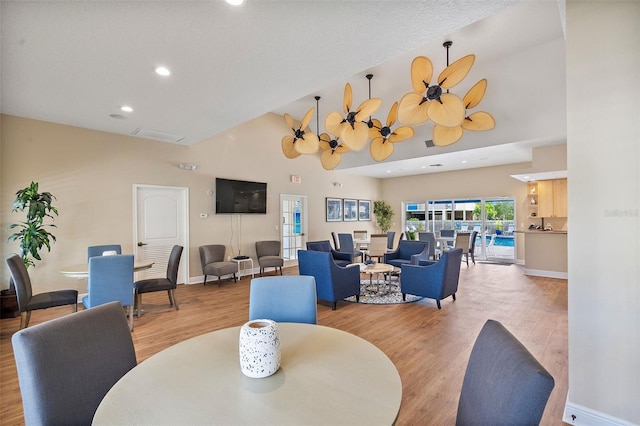 dining space featuring light wood finished floors, high vaulted ceiling, and baseboards