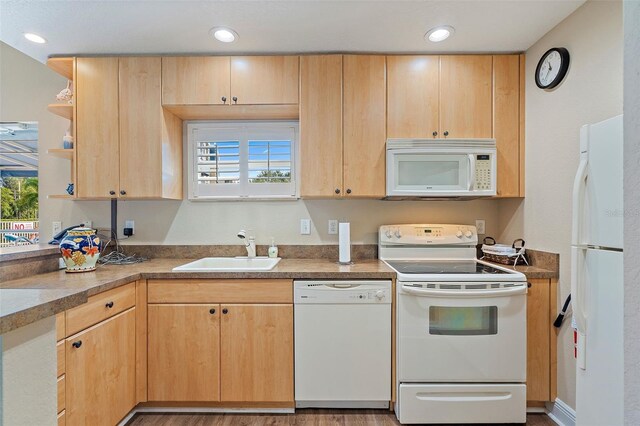 kitchen featuring light brown cabinetry, recessed lighting, white appliances, and a sink