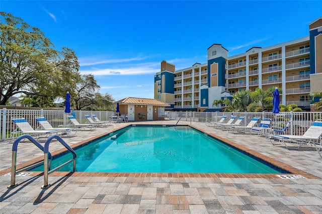 community pool with a patio area and fence