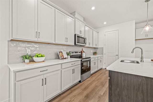 408 W Paris St, Tampa, FL 33604 - kitchen with appliances with stainless steel finishes, light wood finished floors, pendant lighting, backsplash, and light stone countertops