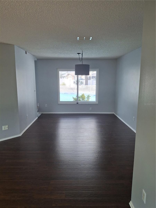 unfurnished room with a textured ceiling, baseboards, and dark wood-type flooring