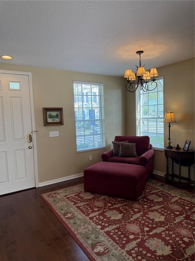 sitting room with dark wood-style floors, a chandelier, and a textured ceiling