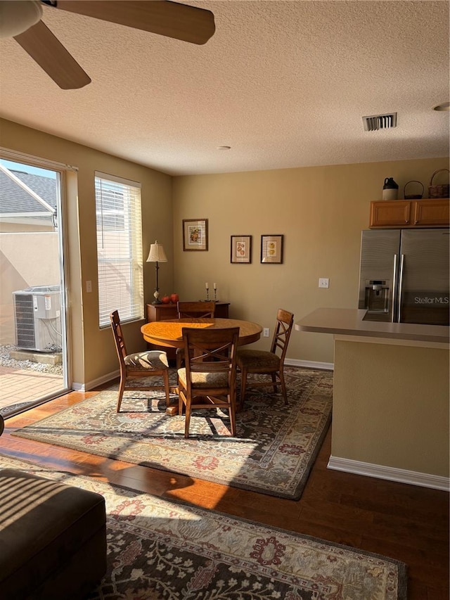 dining area featuring dark wood-type flooring, visible vents, ceiling fan, and baseboards