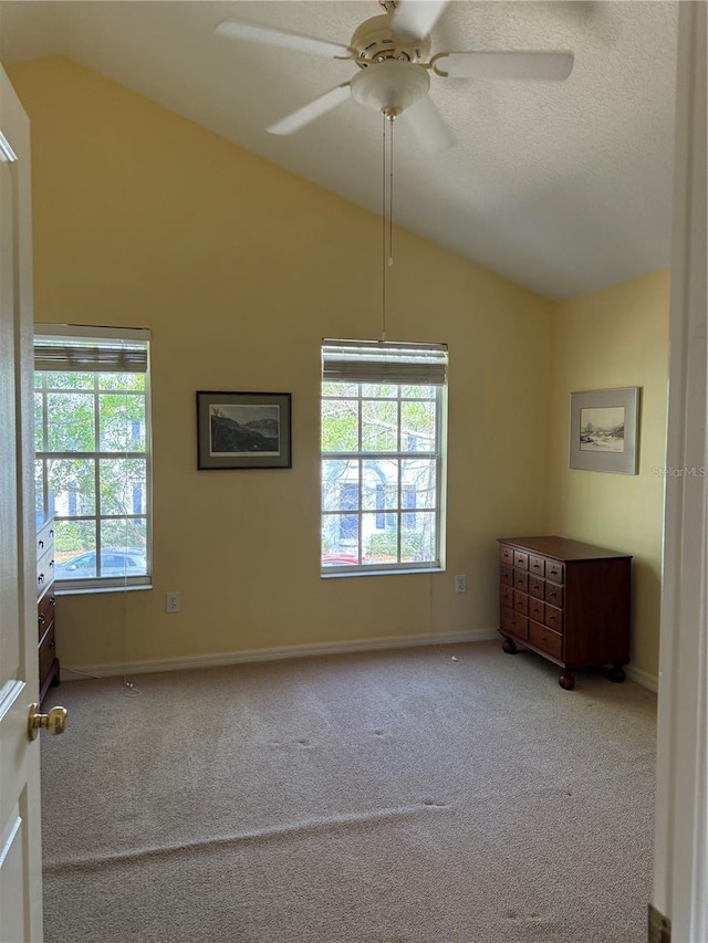 empty room with carpet floors, lofted ceiling, a ceiling fan, a textured ceiling, and baseboards