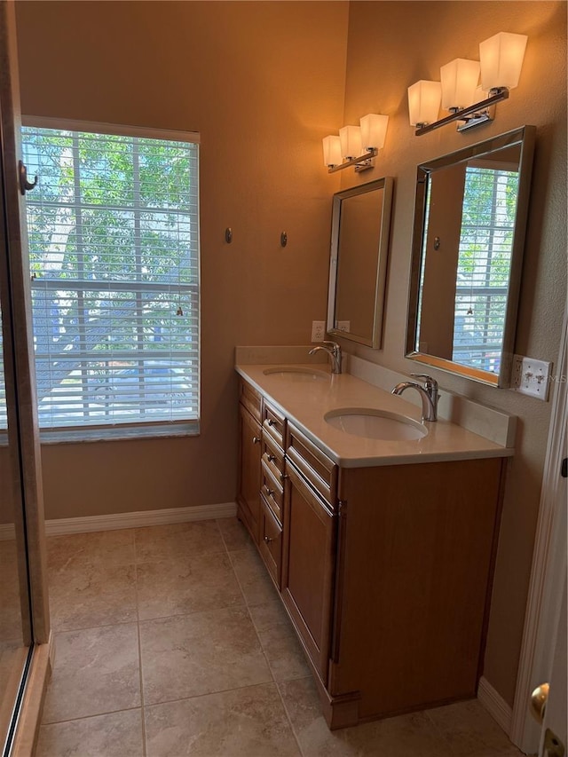 bathroom with double vanity, tile patterned flooring, a sink, and baseboards