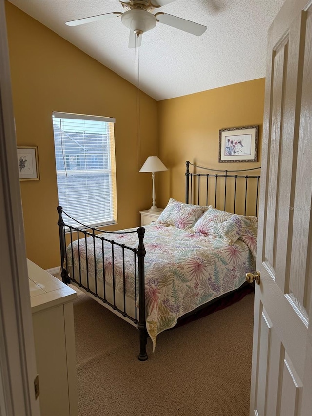 carpeted bedroom featuring ceiling fan, vaulted ceiling, and a textured ceiling