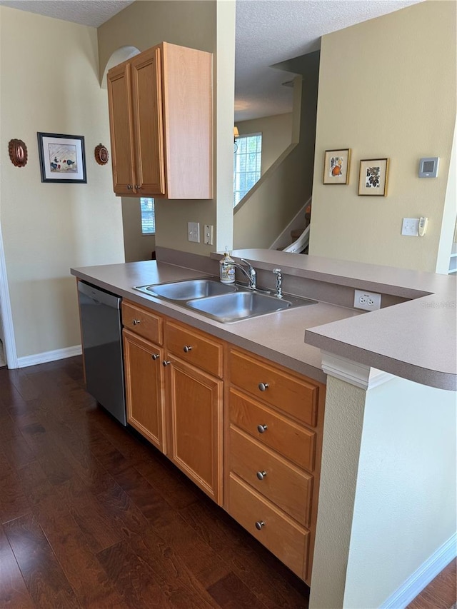 kitchen with a peninsula, dishwashing machine, dark wood-style floors, and a sink