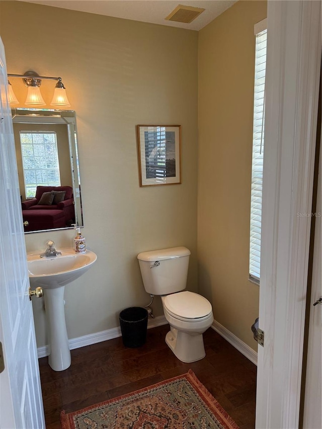 bathroom with baseboards, visible vents, toilet, and wood finished floors