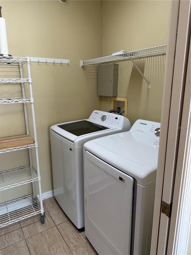 washroom featuring laundry area, baseboards, separate washer and dryer, and light tile patterned flooring