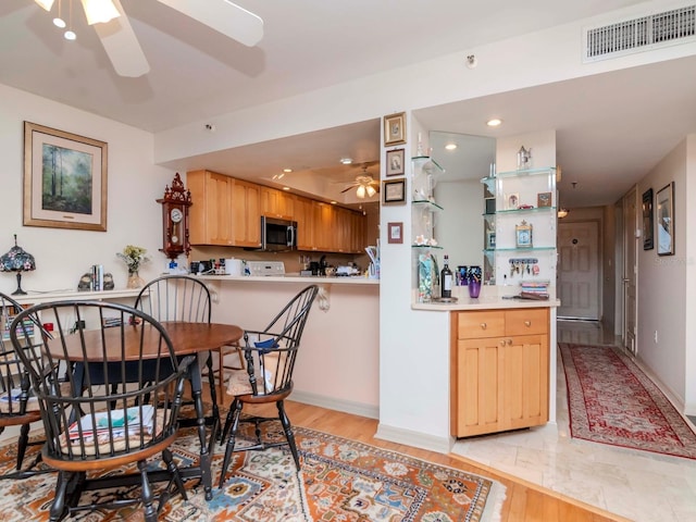 kitchen featuring visible vents, stainless steel microwave, light countertops, light wood-style floors, and a ceiling fan