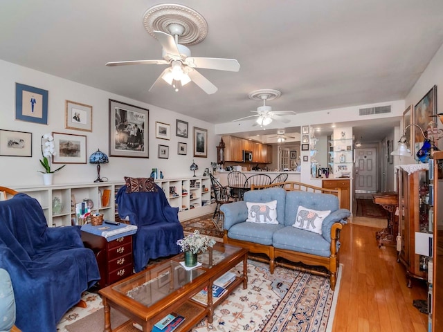 living room featuring light wood-style floors, visible vents, and ceiling fan