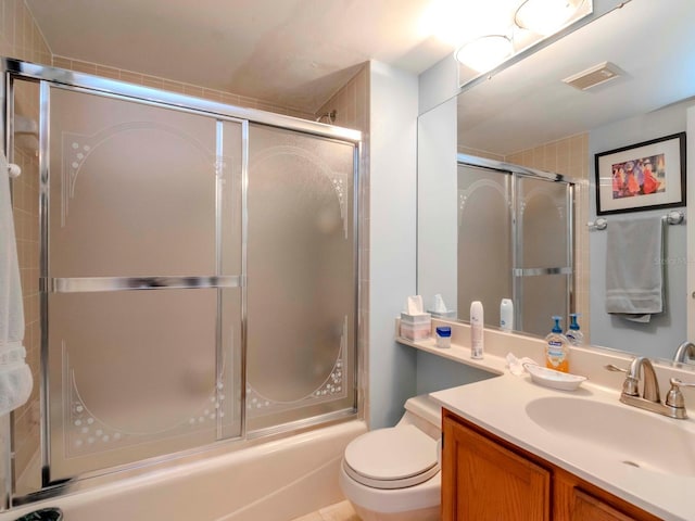 bathroom featuring visible vents, vanity, toilet, and shower / bath combination with glass door